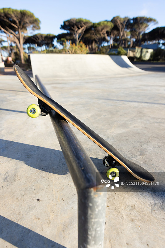 滑板公园的铁轨上的滑板平衡，准备好进行技巧和特技，复制空间图片素材