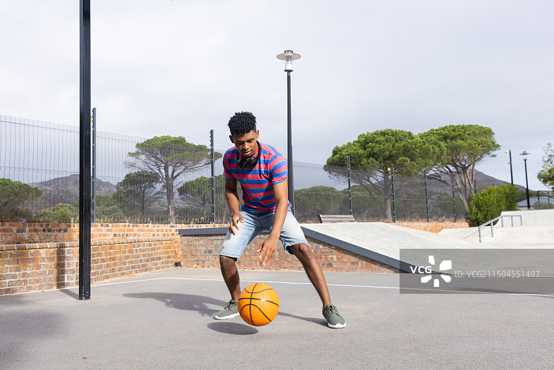 在户外打篮球，男人在球场上运球，休闲装扮图片素材