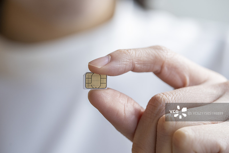 年轻女人的指尖拿着Micro SIM卡图片素材
