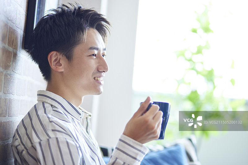 在客厅放松的年轻日本男人图片素材