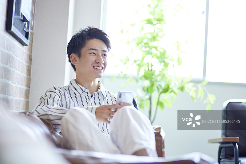 年轻的日本男子在客厅放松图片素材