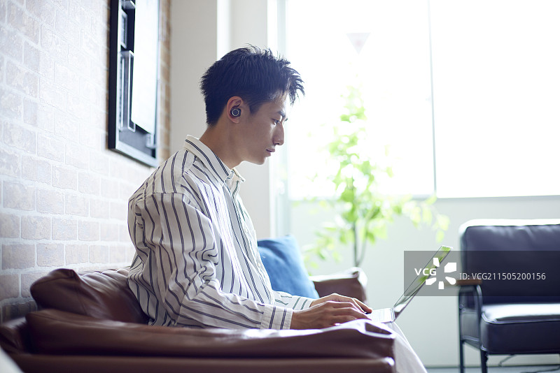 在客厅放松的年轻日本男人图片素材