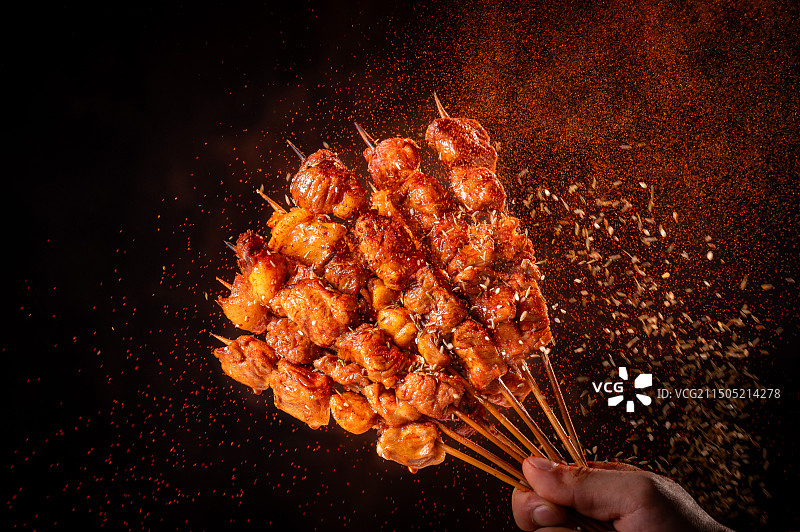 黑色背景下手持烧烤的特写镜头图片素材