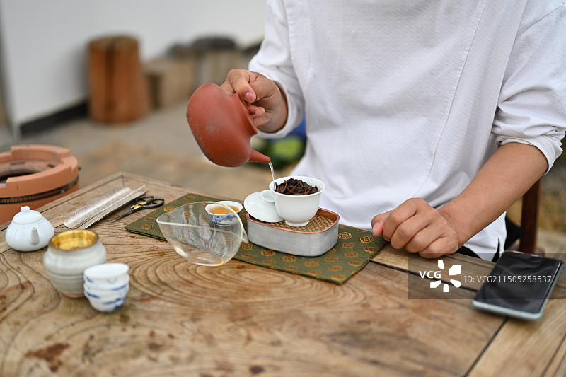 桌子上倒茶的人的中间部分特写图片素材