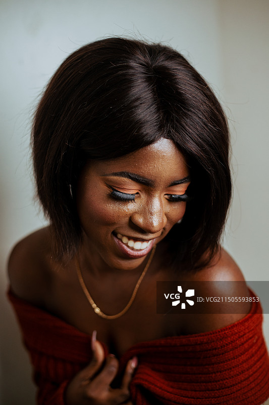 微笑的年轻女人靠墙站立并看向远方特写图片素材