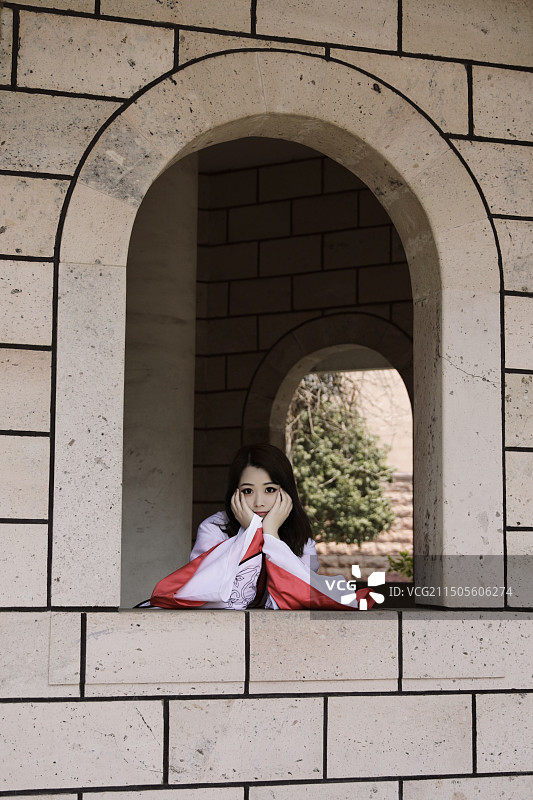 穿着汉服趴在城墙窗户上托腮凝视的旅行少女图片素材