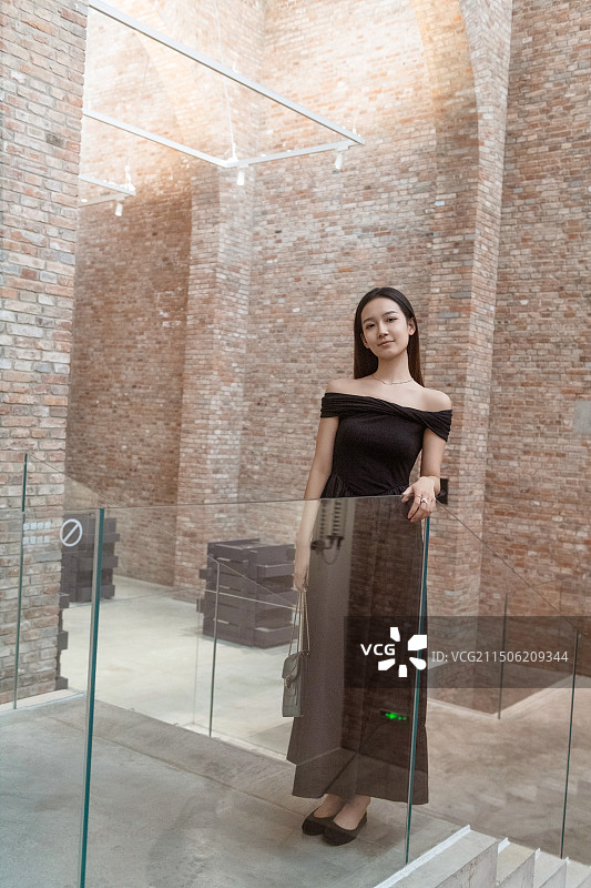 在艺术馆里站着的年轻女子 红色的砖墙图片素材