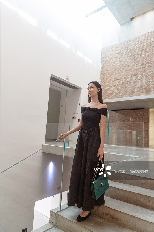 在艺术空间楼梯间站着的年轻女子图片素材
