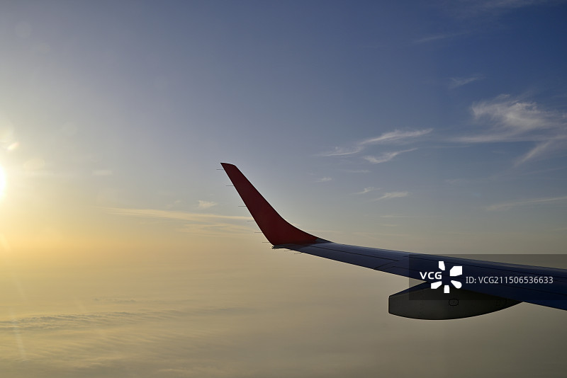 飞机机翼在日落时迎着天空飞行的裁剪图像图片素材