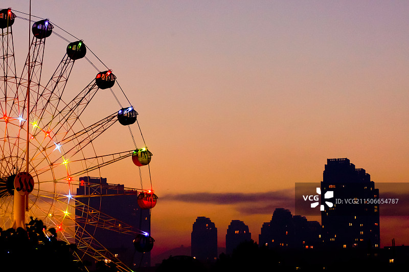 日落时城市上空的摩天轮特写图片素材