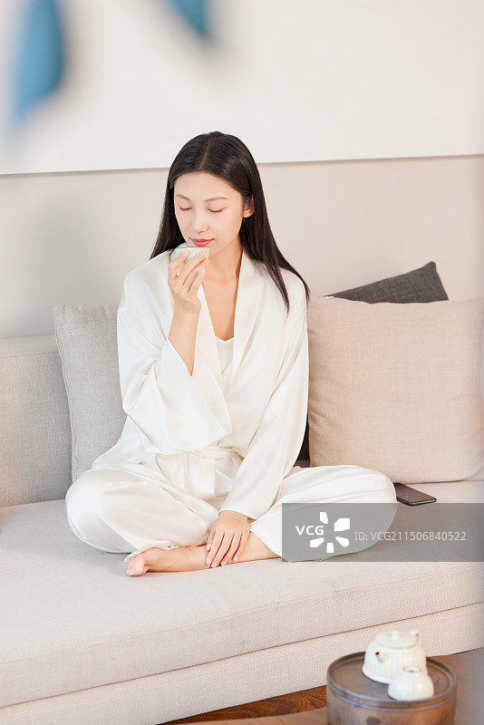 在沙发上喝茶的年轻女人图片素材