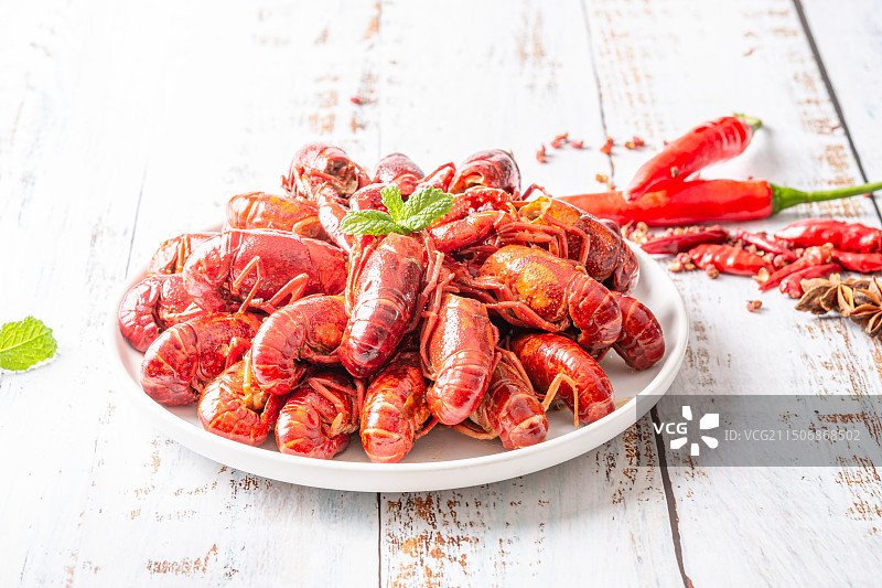 木纹桌面上白色瓷碗里的麻辣小龙虾图片素材