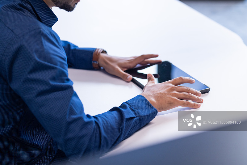 使用平板电脑和智能手机，商人在办公室的桌子上工作，有文案空间图片素材