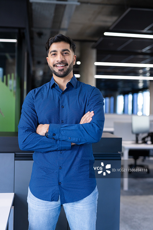 现代办公室里微笑的男商人，穿着蓝色衬衫图片素材