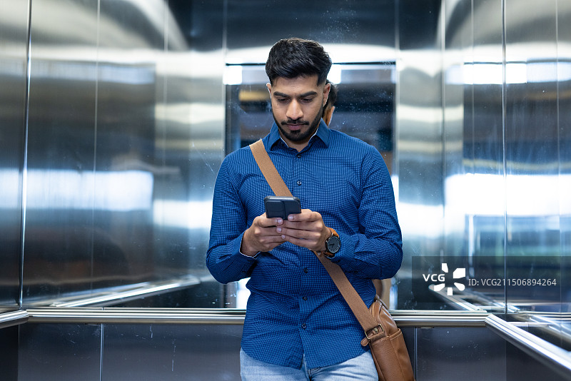 男人在电梯里使用智能手机查看消息图片素材