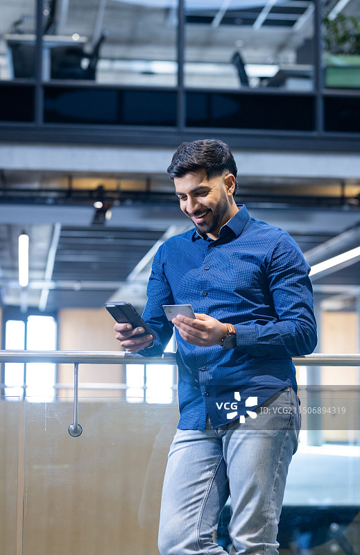 在现代办公室里使用智能手机和信用卡的商人图片素材