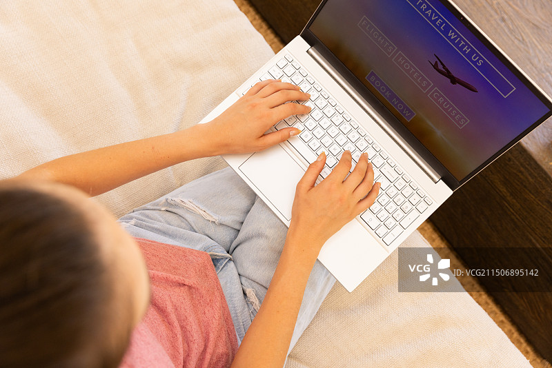 预订旅行：女人在家使用笔记本电脑进行旅行计划图片素材
