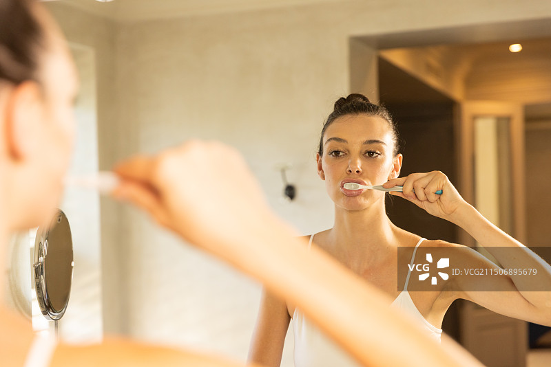 在浴室镜子前刷牙的女人图片素材