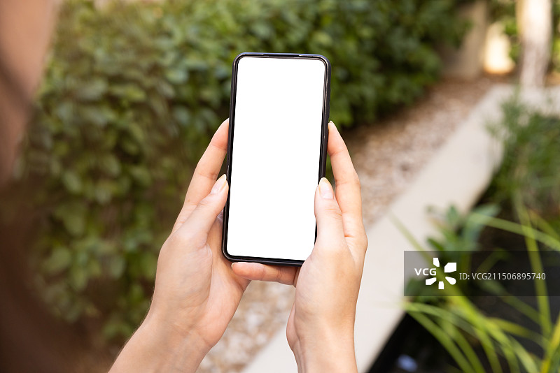 在花园中手持空白屏幕智能手机的人图片素材