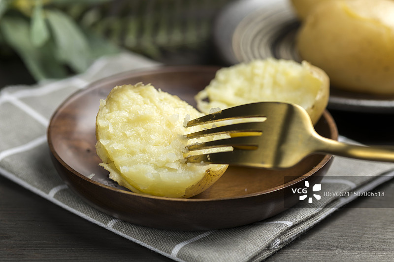 一盘蒸土豆摆放在木桌面上特写图片素材