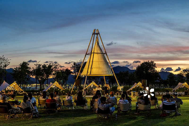 日落时人们在露营地上享受音乐会图片素材