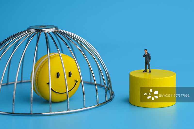 站在牢笼外面思考的男士和牢笼中的笑脸微缩创意图图片素材