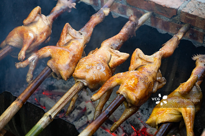 农家土灶柴火烤竹竿串着的多只全鸡图片素材