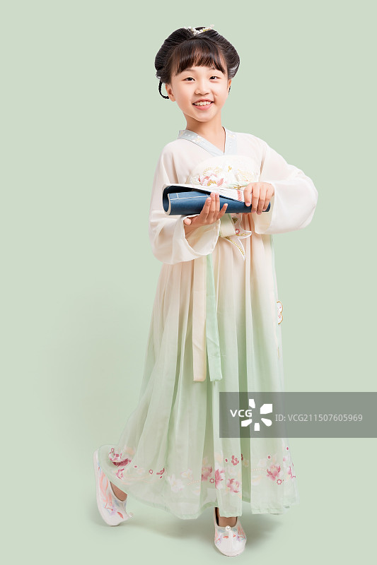 身穿中国古典唐装手拿古书的小女孩棚拍肖像图片素材