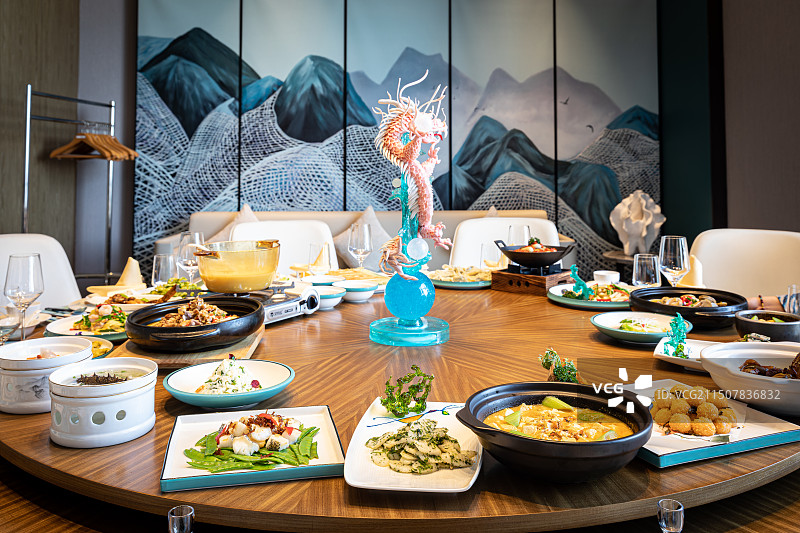 包间里圆桌上摆满了丰富多样的中式宴会菜图片素材