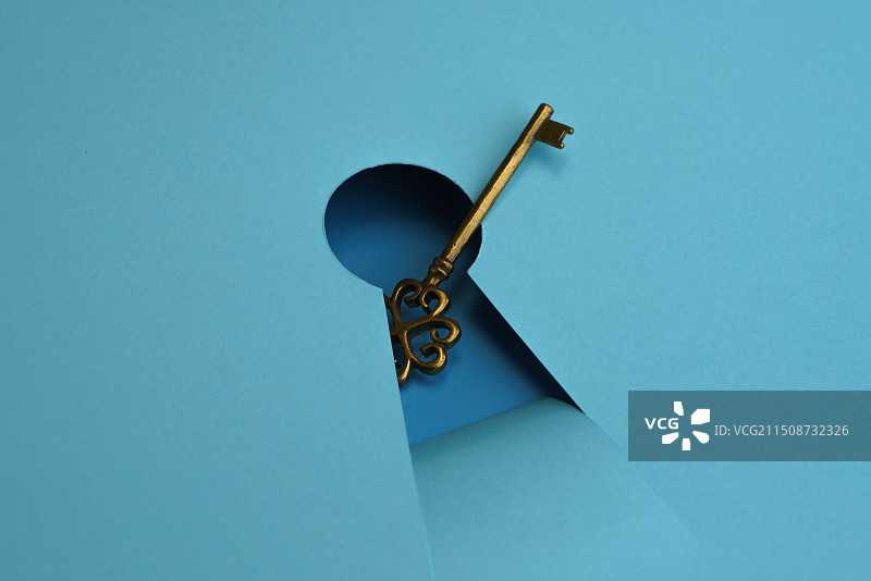 蓝色背景中放在钥匙孔处的钥匙微缩创意图图片素材