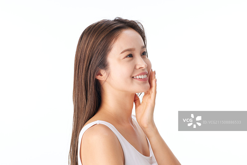 微笑抚摸脸庞的亚洲女人图片素材