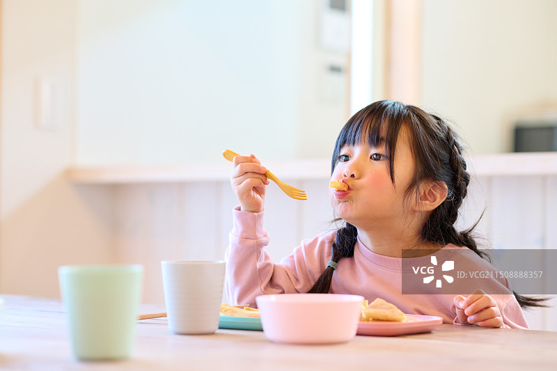 年轻的亚洲女孩在桌旁用餐图片素材