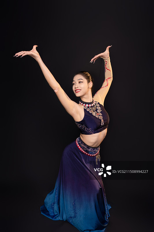 黑色背景中傣族美女身着传统裙子跳舞，展示中国文化魅力图片素材