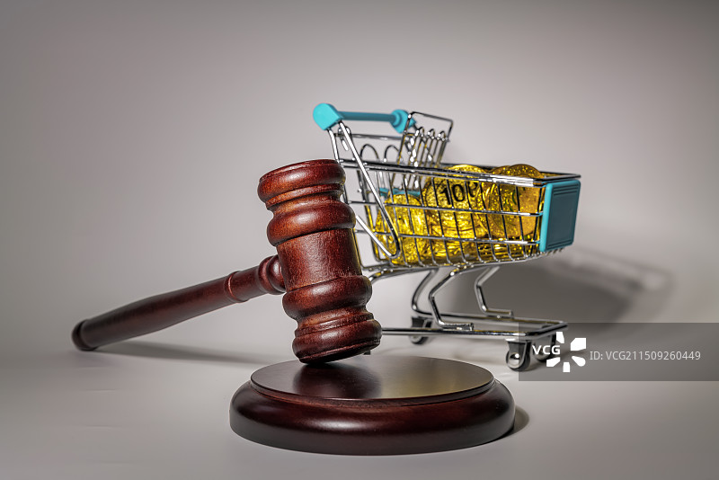 白色背景下购物车中的金币和法槌的特写镜头图片素材