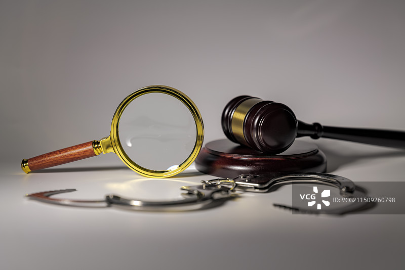 白色背景下放大镜手铐和法槌的特写镜头图片素材
