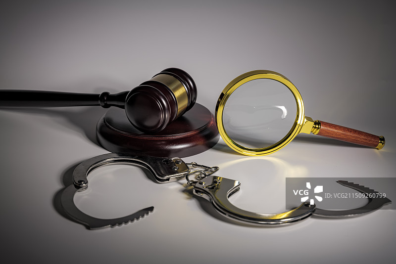 白色背景下放大镜手铐和法槌的特写镜头图片素材
