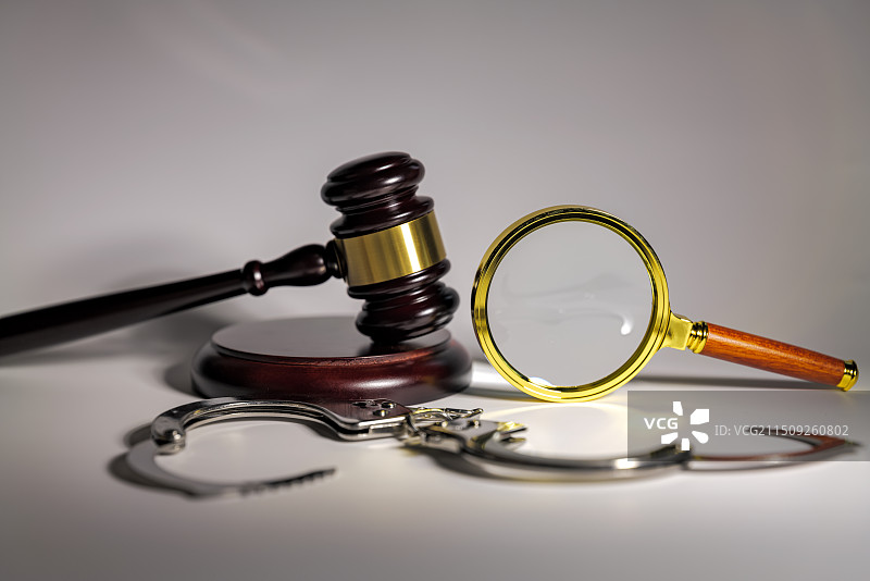 白色背景下放大镜手铐和法槌的特写镜头图片素材
