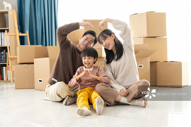 快乐的一家三口坐在搬家的房间里图片素材