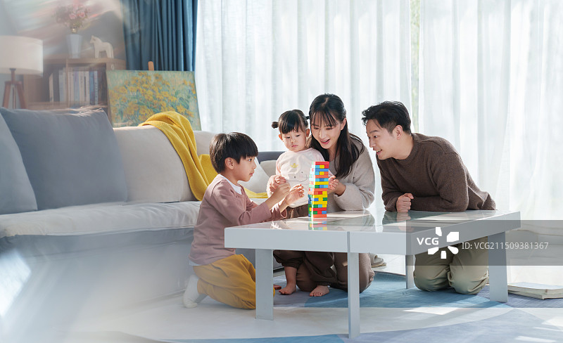 青年父母陪伴孩子在房间里玩玩具图片素材
