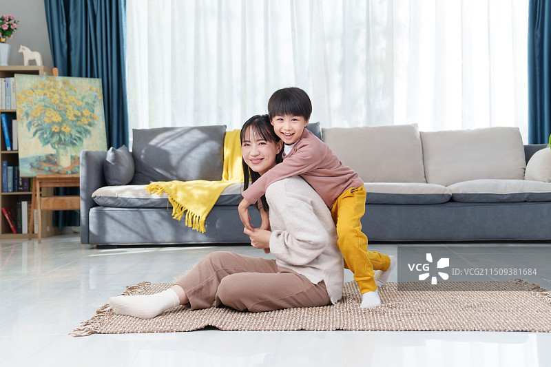 房间里一位亚洲华裔母亲陪伴儿子坐在地板上玩耍图片素材