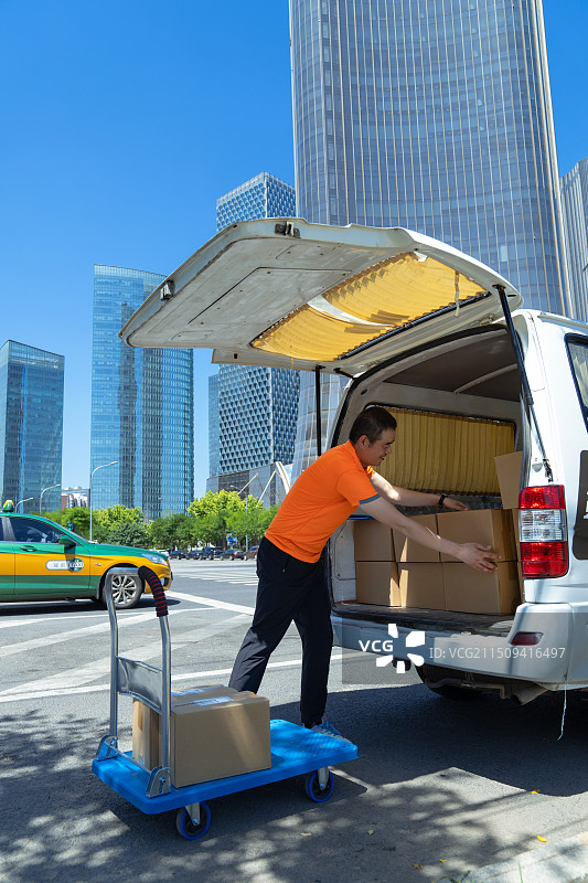 快递员将包裹装上推车图片素材