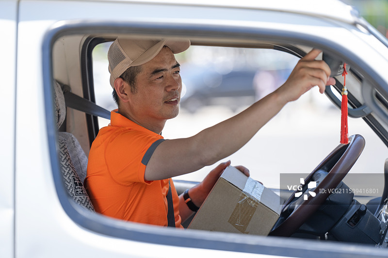 车内驾驶货车配送包裹的快递员图片素材