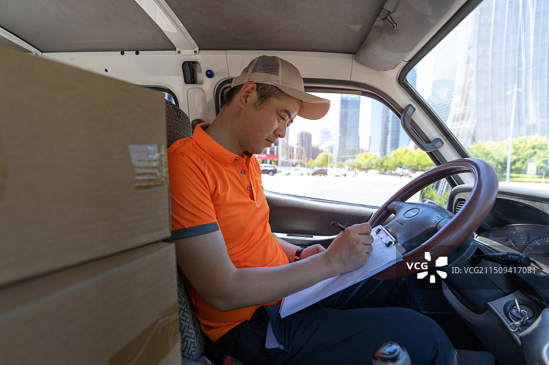 车内驾驶货车配送包裹的快递员图片素材