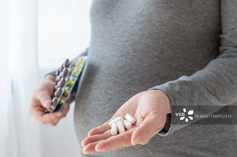 一位年轻孕妇手里拿着钙片和维生素图片素材