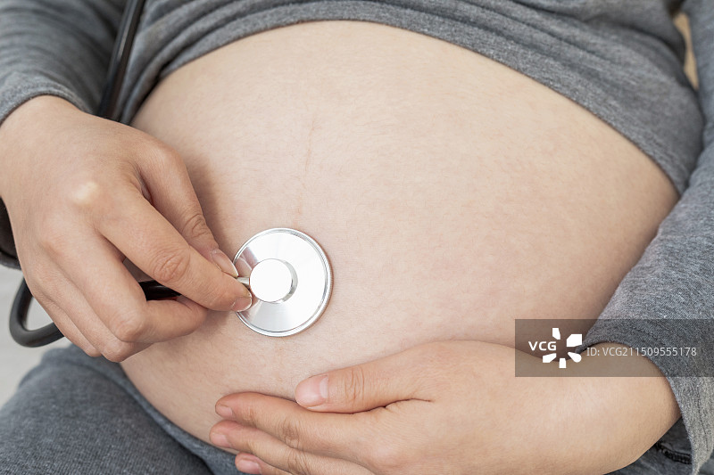 室内一名中国年轻孕妇使用听诊器图片素材