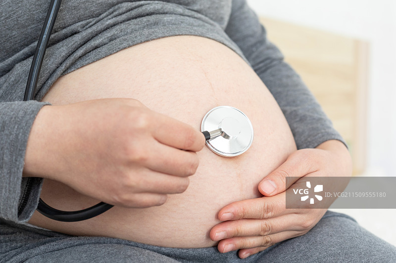 室内一名中国年轻孕妇使用听诊器图片素材