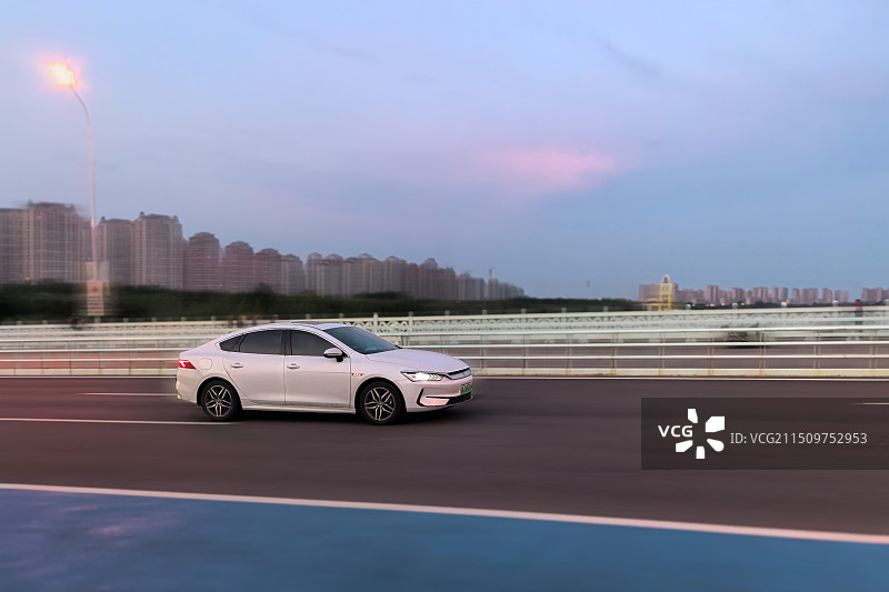 夕阳美景下，抓拍白色轿车飞驰而过的画面图片素材