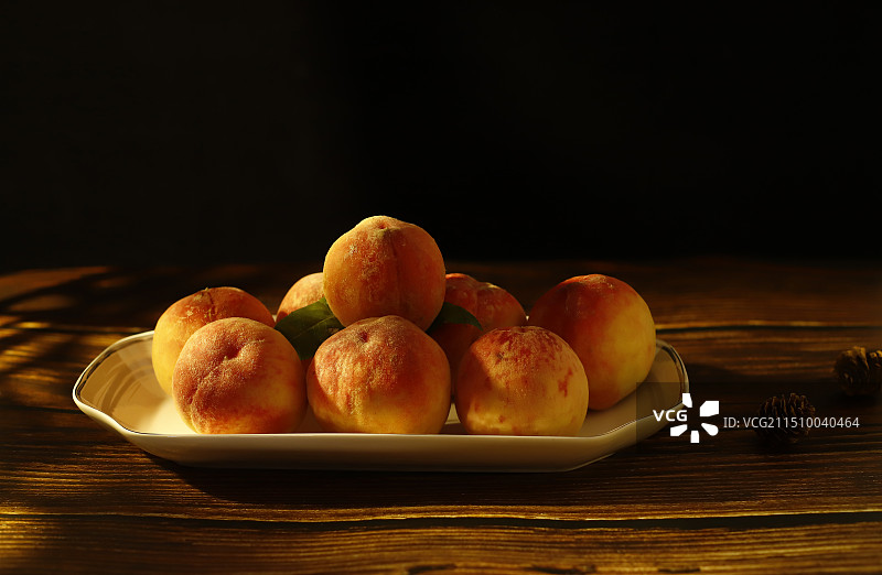 黑色背景下桌上盘子里桃子的特写镜头图片素材