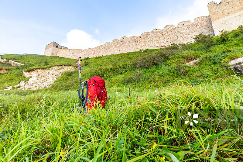 一个红色的登山包放在长城脚下图片素材