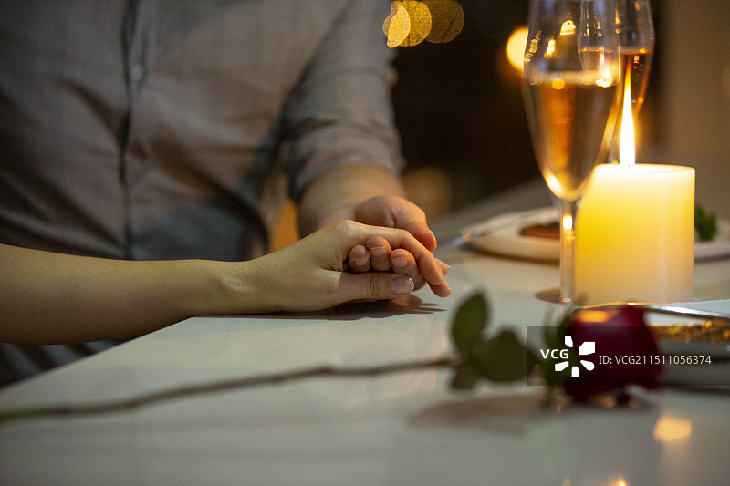 年轻情侣共进晚餐，手牵手特写图片素材